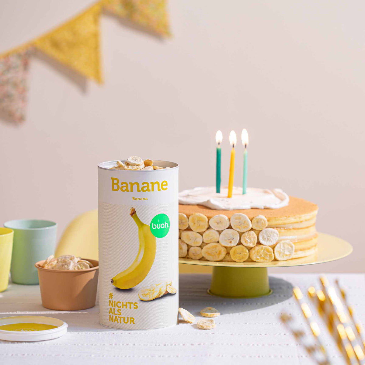 Dose buah Banane neben einem Geburtstagskuchen, dekoriert mit buah Bananen