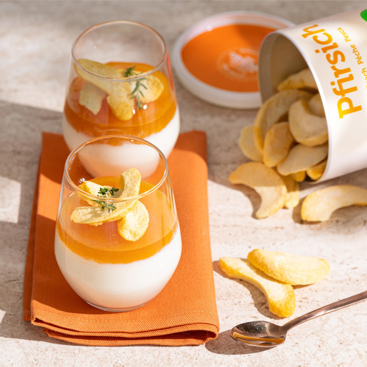 Umgekippte Dose buah Pfirsich mit herausfallenden Pfirsich Schnitzen neben zwei Pfirsich Desserts