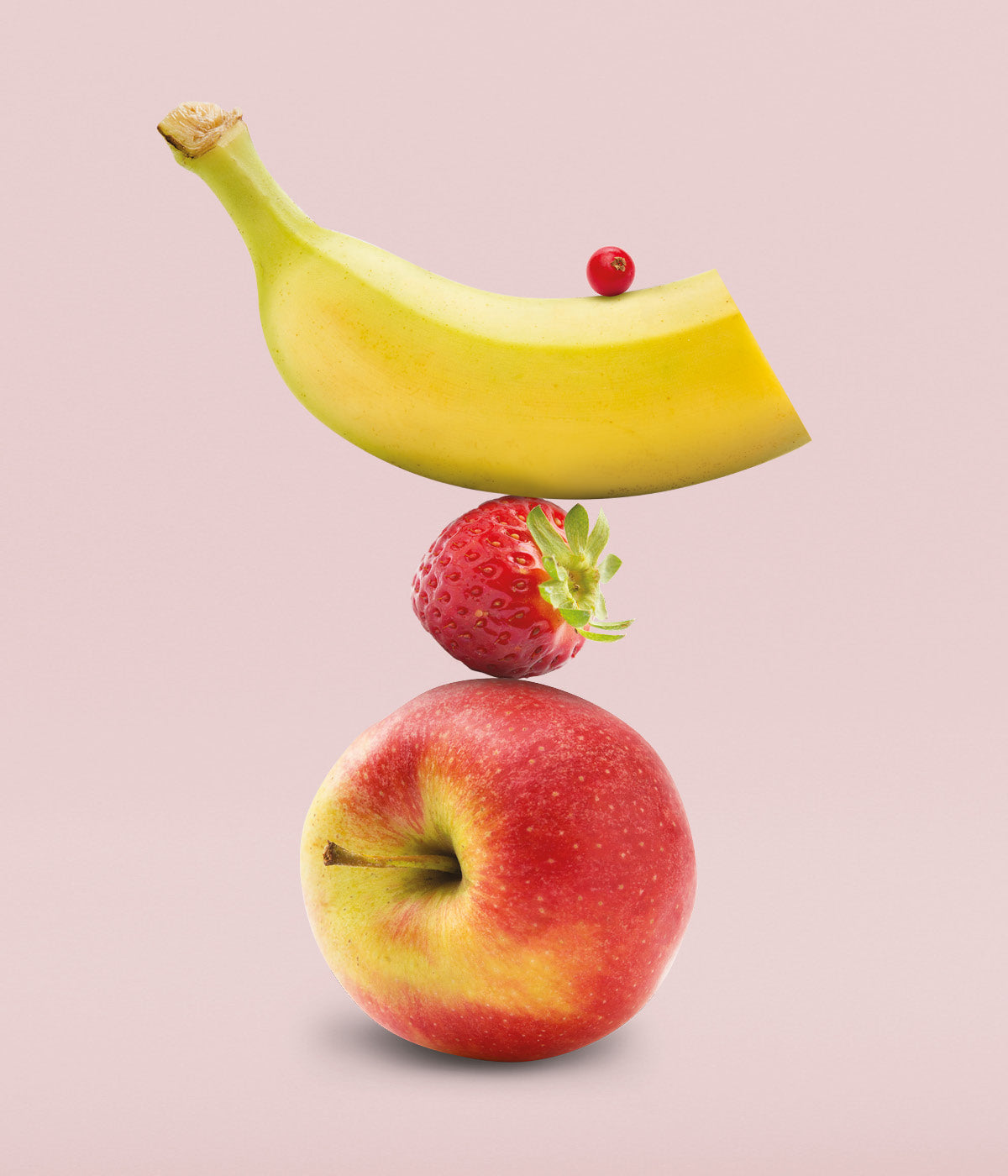 Frische Johannisbeere, Banane und Erdbeere balancieren sich gestapelt auf frischem Apfel