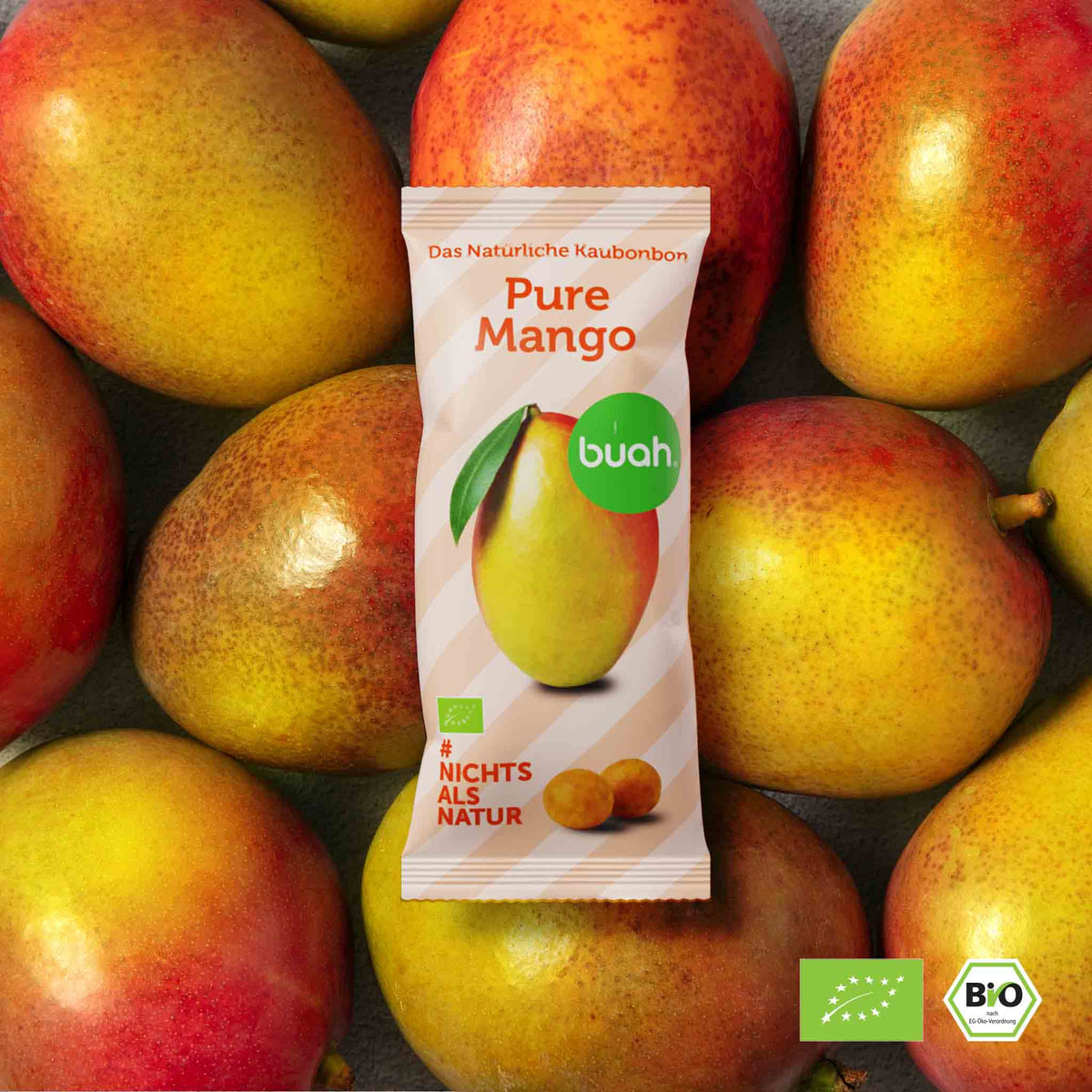 Pure Mango Kaubonbon Packung liegt auf vielen rot-orangenen Mangos