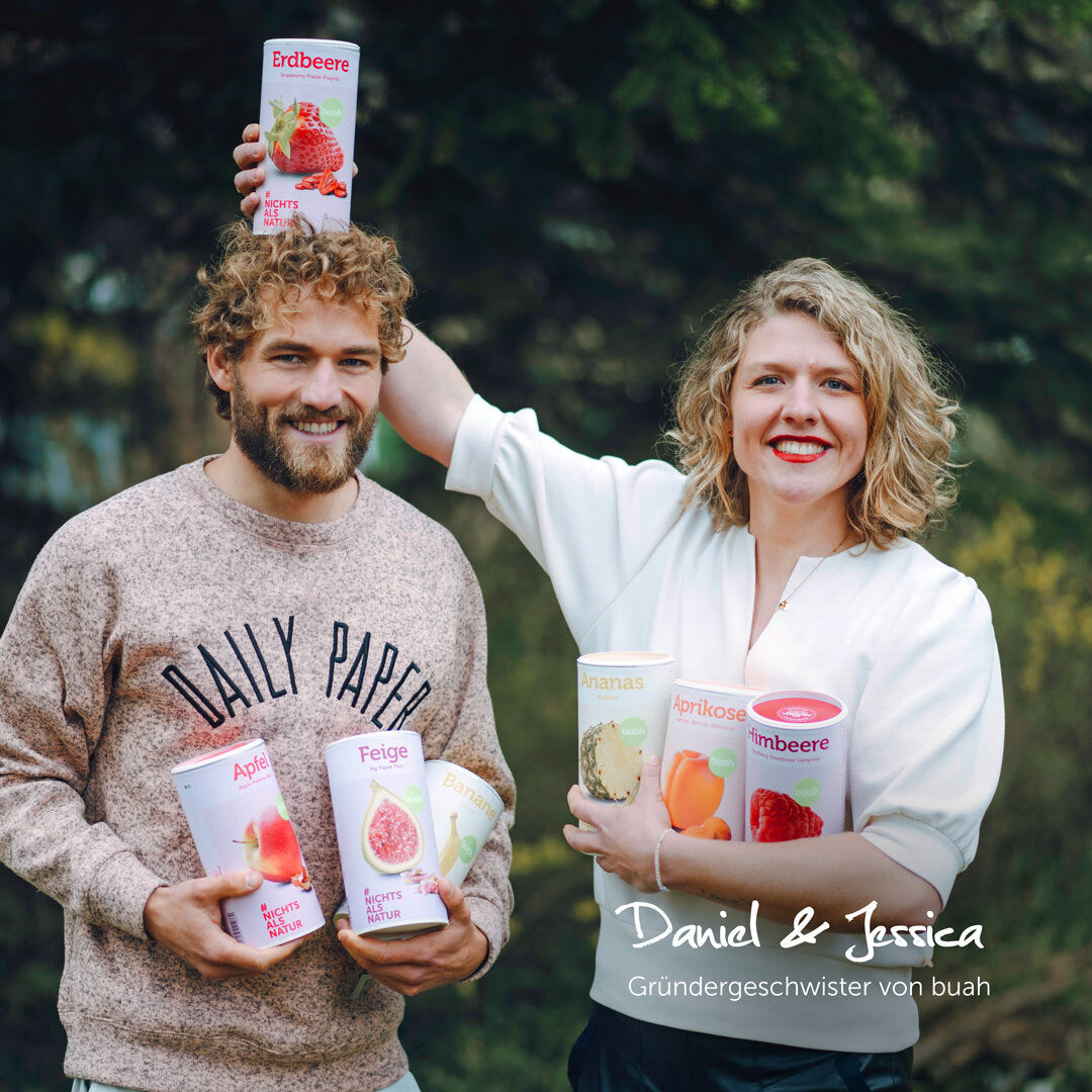 buah Gruendergeschwister Daniel und Jessica Krauter lachen in die Kamera, mit buah Dosen in der Hand, Jessica haelt buah Dose Erdbeere ueber Daniels Kopf