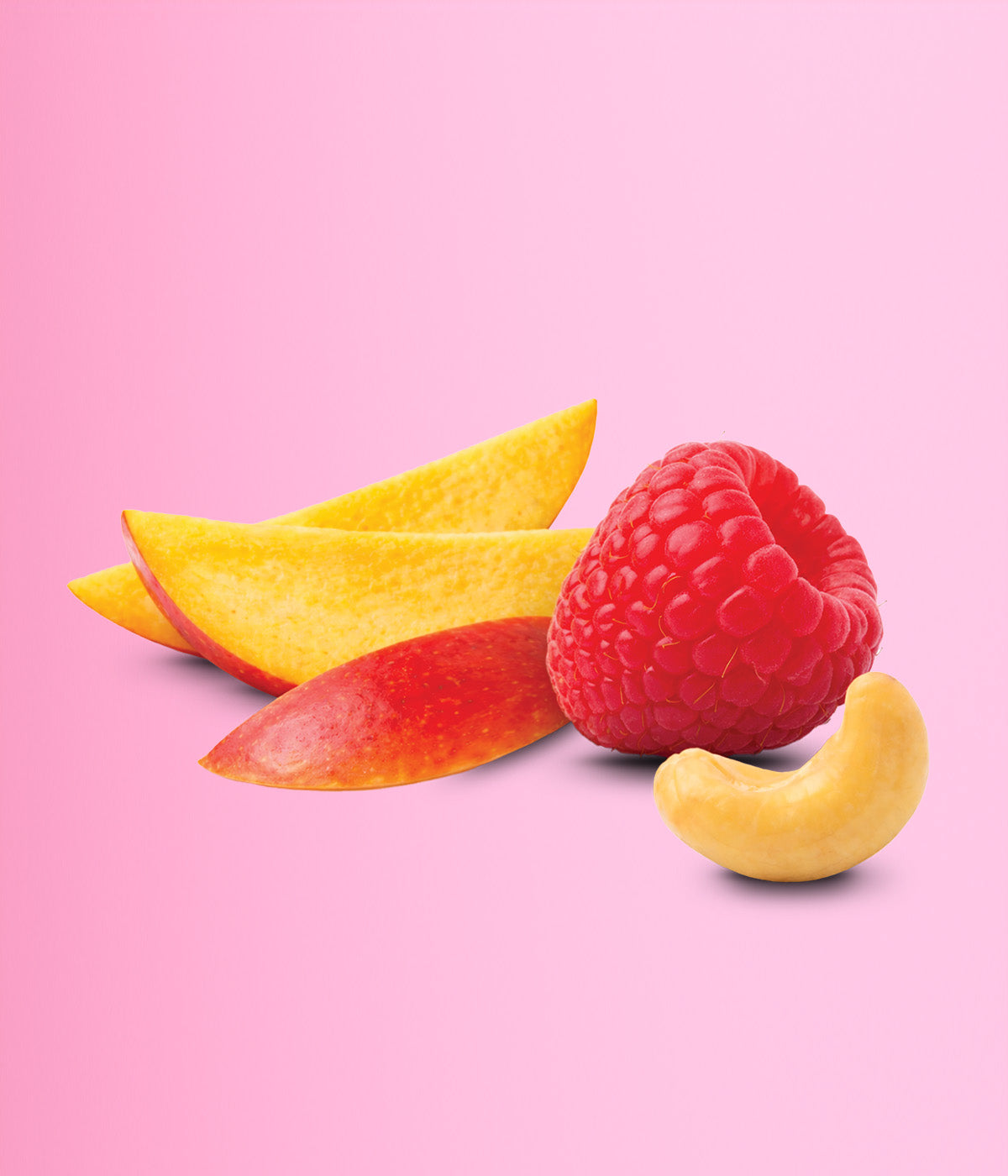 Ein Arrangement aus frischen Zutaten vor einem pinken Hintergrund. Zu sehen sind zwei Mangoschnitze, eine Himbeere und ein Cashewkern.