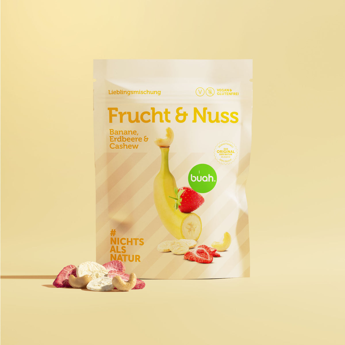 Packung buah Frucht & Nuss Mischung mit Banane, Erdbeere & Cashew vor gelbem Hintergrund