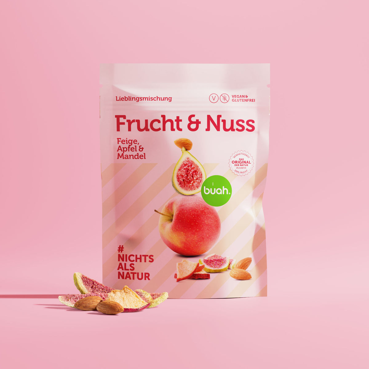 Packung buah Frucht & Nuss Mischung der Sorte Feige, Apfel und Mandel vor rosa Hintergrund