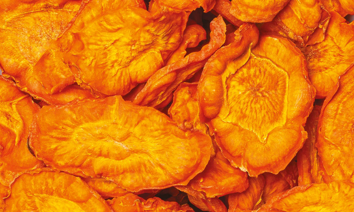 Viele orangene, knackige und vakuumgetrocknete Karottenchips neben und aufeinander
