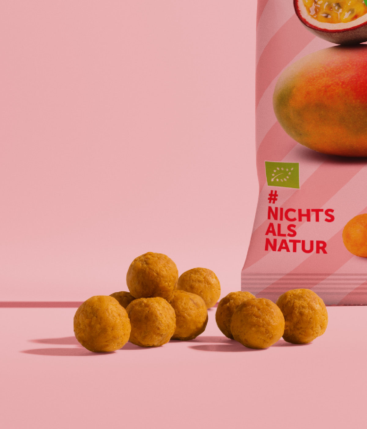 Runde, orange Mango-Maracuja Kaubonbons liegen vor einer Verpackung der Kaubonbons