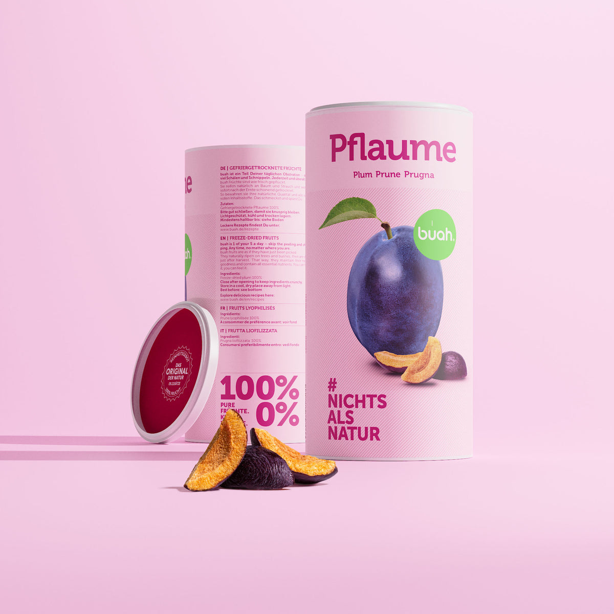 Zwei Grosse Dosen buah gefriergetrocknete Pflaume vor rosa Hintergrund mit dem Abbild einer frischen Pflaume auf der Dose. Gefriergetrocknete Pflaume liegt vor der Dose. 