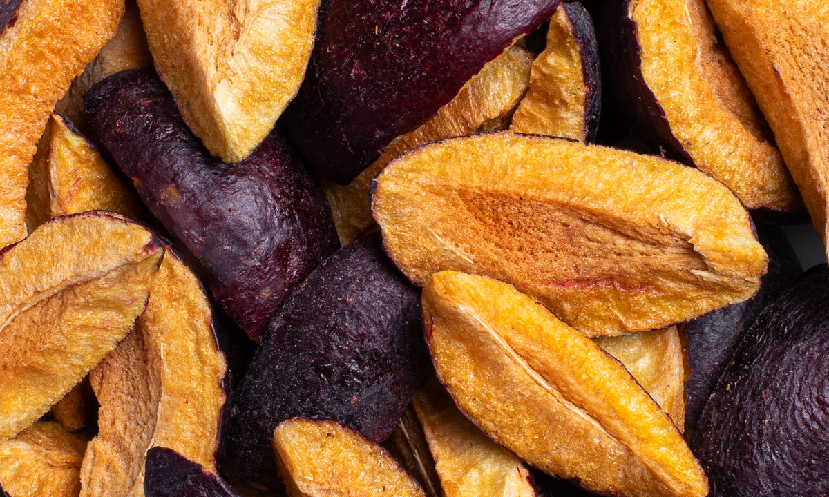 Viele Schnitze der buah gefriergetrockneten Pflaume in kraeftiger oranger und lila Farbe liegen auf und nebeneinander 